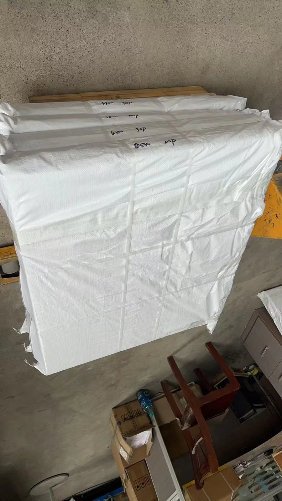 Palletised finished goods in white woven bags, marked with handwritten batch numbers