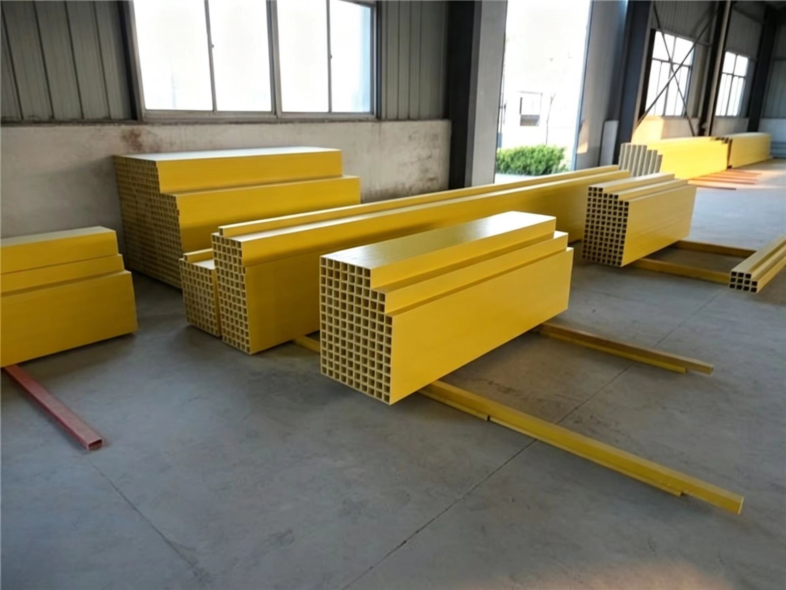 Pultruded fiberglass profiles stacked in the workshop store, seen from the aisle